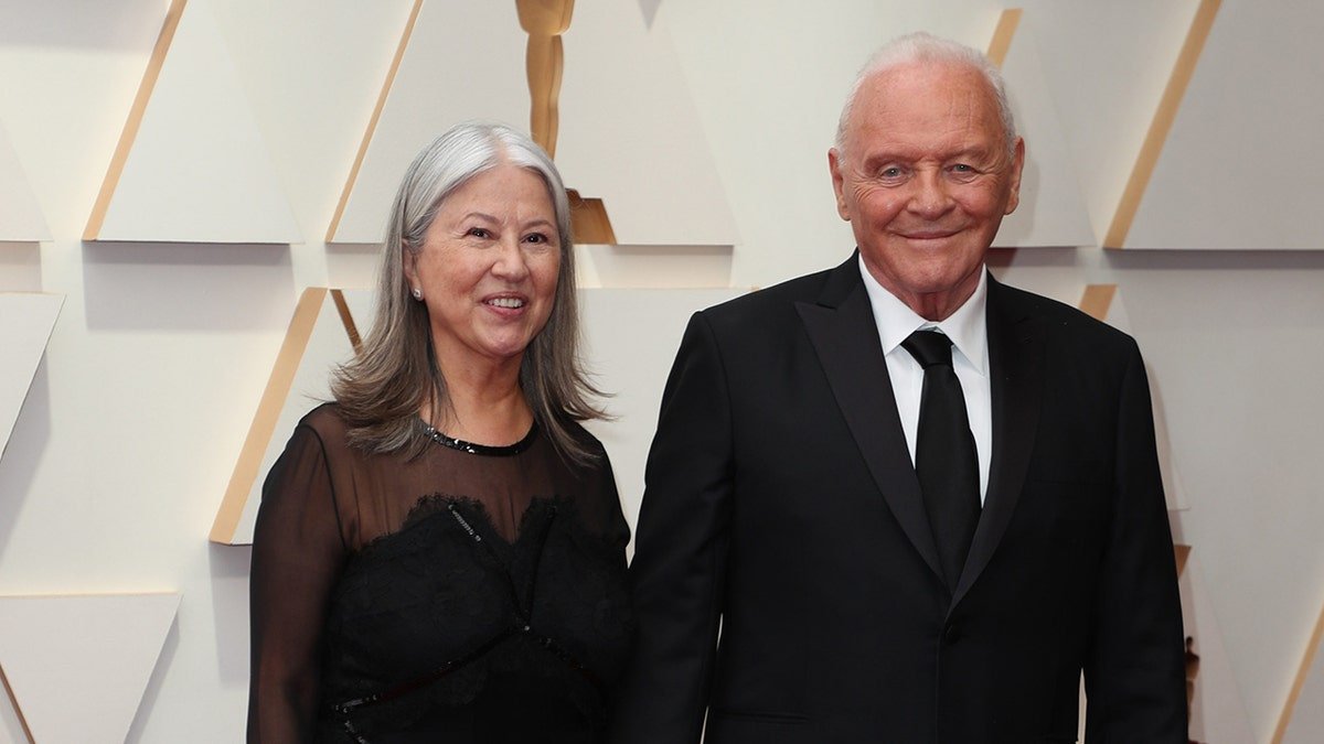 Anthony Hopkins porte un costume et une cravate noirs avec sa femme Stella.