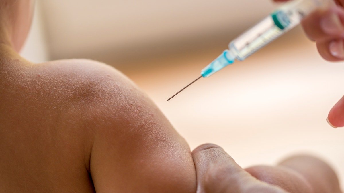Le médecin injecte à un petit enfant un vaccin ou un antibiotique dans une petite seringue hypodermique jetable, gros plan sur le bras et l'aiguille de l'enfant.