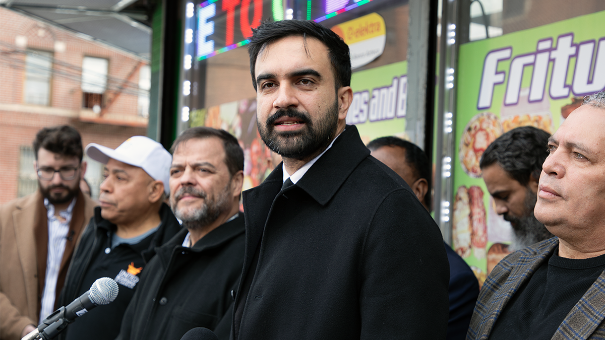 Zohran Mamdani porte un manteau noir.