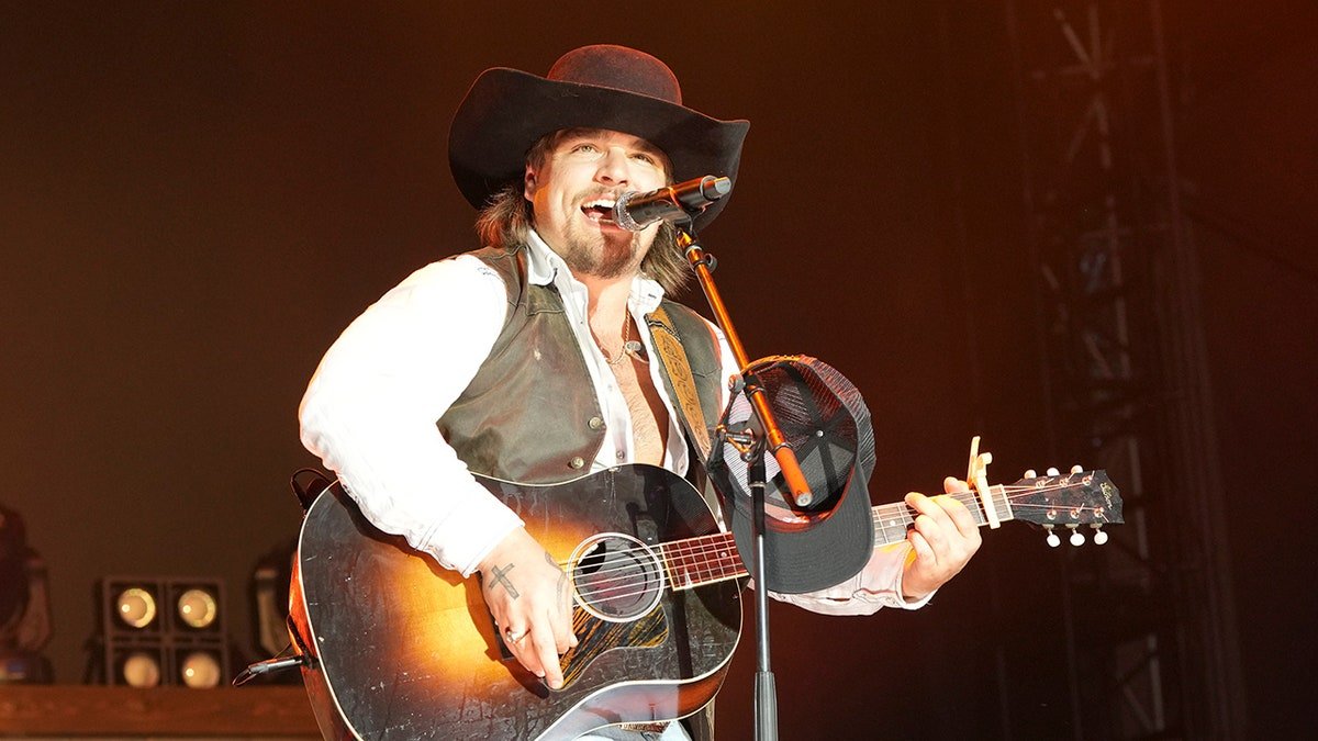 Gavin Adcock chante et joue de la guitare en concert