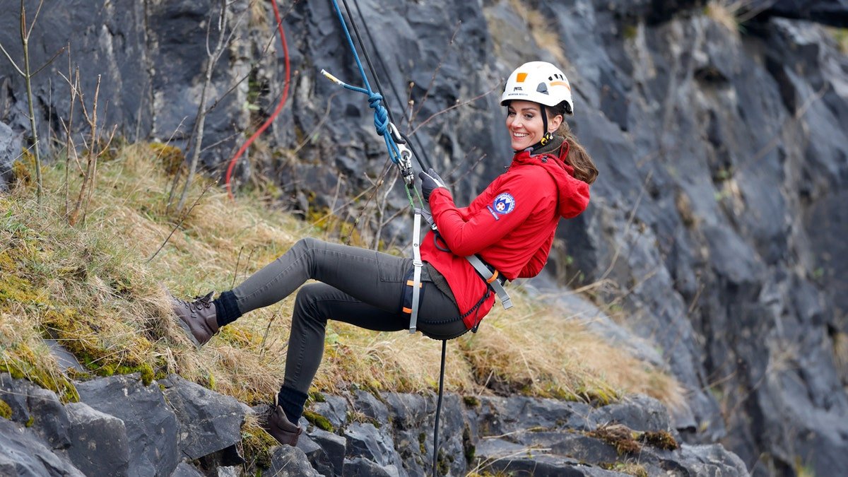 Kate Middleton porte un casque et une veste rouge pendant l'escalade
