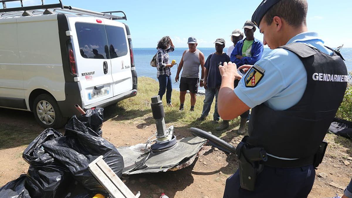 Un gendarme français prend une photo des débris ramassés par des membres d'associations environnementales locales et des bénévoles dans la partie orientale de Sainte-Suzanne sur l'île française de la Réunion dans l'océan Indien lors des opérations de recherche du vol MH370 disparu par les forces françaises et les associations locales le 11 août 2015. Les recherches du vol MH370 disparu se poursuivront le 30 décembre.